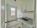 Laundry room features white cabinets, granite countertops, and a window at 2906 Lathan Rd, Monroe, NC 28112