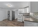 Functional kitchen with stainless steel refrigerator, white appliances, and updated cabinets at 413 Shinnville Rd, Mooresville, NC 28115