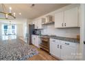 Bright kitchen featuring stainless steel appliances, white cabinets, granite countertops, and wood flooring at 9489 Westridge Dr, Hickory, NC 28601