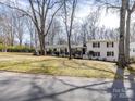 Wide angle view of a white home with well manicured shrubbery and a long walkway to the front door at 1116 Circlewood Dr, Charlotte, NC 28211
