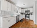 Bright kitchen features white cabinets, stainless steel appliances, subway tile backsplash, and hardwood flooring at 1116 Circlewood Dr, Charlotte, NC 28211
