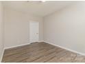 A minimalist bedroom showcasing wood flooring and a door at 14967 Santa Lucia Dr, Charlotte, NC 28277
