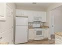 Bright kitchen boasts white appliances, white cabinetry, and stylish backsplash at 14967 Santa Lucia Dr, Charlotte, NC 28277