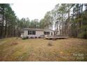 Tan mobile home with wooden deck, nestled in wooded area at 210 Barbary Dr, Statesville, NC 28677