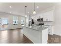 Modern kitchen with white cabinets, stainless steel appliances, island, and hardwood floors at 3036 Arbor Ash St # 1022B, Charlotte, NC 28208