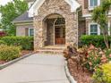 Close-up of the stone entryway with a double wooden door and landscaped surroundings at 3850 Hounslow Ln, Harrisburg, NC 28075