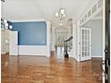 Elegant living room featuring hardwood floors, decorative molding, blue accent wall, and staircase access, showcasing the home's interior at 4407 Esherwood Ln, Charlotte, NC 28270