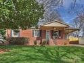 Charming brick home featuring a well-manicured lawn and inviting covered front porch with table set at 833 Montford Dr, Charlotte, NC 28209