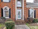 Close up of a brick home's front entrance showing the door, windows, and beautiful plants surrounding the entrance at 11107 Balata Ct, Charlotte, NC 28269