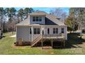 Rear view of the house featuring a wooden deck, multiple windows, and access to the backyard at 704 Kenway Loop, Mooresville, NC 28117
