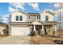 Two-story house with gray siding, stone accents, and a three-car garage at 12613 Stoneybrook Station Pkwy, Huntersville, NC 28078