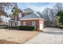 Two-story brick home featuring an attached garage, manicured landscaping, and a long driveway at 133 Castaway Trl, Mooresville, NC 28117