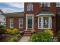 Close-up of the front entrance with a glass front door, brick facade, and colorful potted plants at 133 Castaway Trl, Mooresville, NC 28117