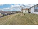 Landscaped backyard with a sloped lawn and black fence at 6297 Raven Rock Dr, Denver, NC 28037