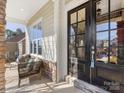 Relaxing front porch with two wicker chairs, a black door, and stone accents at 100 S Centurion Ln, Mount Holly, NC 28120