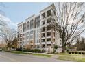 Modern condo building with tree-lined street and parking at 130 Cherokee Rd # 403, Charlotte, NC 28207