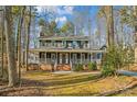 Two-story house with wraparound porch, nestled among trees at 14264 Maple Hollow Ln, Mint Hill, NC 28227