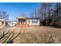 Gray siding house with brick base, wooden porch, and mature trees in the background at 604 Kimball St, Kannapolis, NC 28081