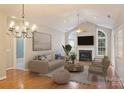 Bright living room featuring vaulted ceilings, a cozy fireplace, and natural light from large arched windows at 8355 Olde Troon Dr, Charlotte, NC 28277