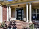 Elegant front entry with columns and a modern black door at 10718 Lederer Ave, Charlotte, NC 28277