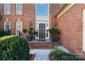 A charming entryway featuring a brick facade, elegant front door, and decorative greenery at 12201 Pine Valley Club Dr, Charlotte, NC 28277