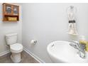 A modern half-bathroom with a pedestal sink, toilet, and towel rack, decorated in neutral tones at 3148 Ora Smith Rd, Lincolnton, NC 28092