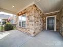 Inviting front porch features brick accents, a black front door, and a cozy, covered seating area at 9029 Treetop Nw Way, Concord, NC 28027