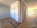 Unfurnished bedroom showing neutral walls and trim, a window, and flooring partially protected during construction at 9934 Cask Way, Huntersville, NC 28078