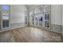 Sun-drenched, all white living room with hardwood floors and large windows with shutters at 10433 Pullengreen Dr, Charlotte, NC 28277