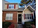 Inviting townhome featuring red shutters, brick facade, and manicured landscaping at 10904 Pimlico Dr, Charlotte, NC 28273