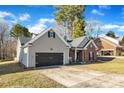 View of the house featuring the garage, partial brick, and lawn with bare trees at 12527 Cedar Post Ln, Charlotte, NC 28215