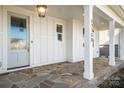 Front porch with stone flooring, white columns, and light fixture at 13308 Oak Farm Ln, Huntersville, NC 28078