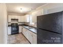 White kitchen cabinets, dark countertops, and a black refrigerator at 2331 Celia Ave, Charlotte, NC 28216