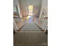 An interior staircase with white wood banisters leads to an open front door allowing natural light to flood the home's entryway at 5972 Rathlin Nw Ct, Concord, NC 28027