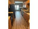 Traditional eat-in kitchen with wood cabinets, black appliances, and hardwood floors, perfect for cooking and dining at 7117 Flying Scotsman Dr, Charlotte, NC 28213