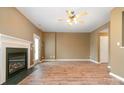 Spacious living room with a fireplace, wood-look floors, ceiling fan and natural light from windows and door at 7117 Flying Scotsman Dr, Charlotte, NC 28213