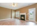 Bright living room featuring fireplace, ceiling fan, wood-look floors, and natural light from windows and the door at 7117 Flying Scotsman Dr, Charlotte, NC 28213