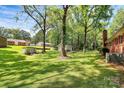 Lush, expansive backyard with mature trees, shed and back of house with brick chimney and HVAC system at 1801 Windsor Dr, Lancaster, SC 29720