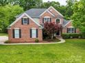 Two-story brick home with a tree and a well-maintained lawn at 8100 Avanti Dr, Waxhaw, NC 28173