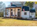 White farmhouse exterior with a dark gray roof, a covered porch and American flag at 910 S College Ave, Newton, NC 28658