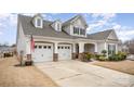 Two-story house with gray siding, three-car garage, and manicured lawn at 12612 Longford Crossing Pl, Huntersville, NC 28078