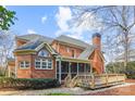 Charming brick home featuring a screened porch, wooden deck, and manicured greenery at 7007 Dowington Dr, Charlotte, NC 28277