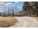 Mobile home with gravel driveway and wooded surroundings at 1762 Proposal Ave, Chester, SC 29706