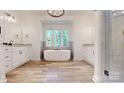 Bright bathroom featuring a soaking tub, double vanities, and wood look tile flooring at 4607 Ferguson Cir, Waxhaw, NC 28173