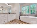 Bright bathroom featuring a soaking tub, vanity, and wood look tile flooring at 4607 Ferguson Cir, Waxhaw, NC 28173