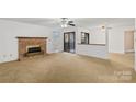 Bright living room featuring a brick fireplace, fan, and sliding glass doors to the outside at 5818 Harris Grove Ln, Charlotte, NC 28212