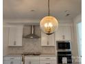 Modern kitchen with stainless steel appliances, white cabinets, and a decorative light fixture at 8768 Sherrills Ford Rd, Sherrills Ford, NC 28673