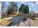 Spacious backyard with gravel, trees, and a wooden fence providing privacy at 114 Juanita Dr, Pineville, NC 28134