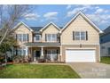 Two-story house with beige siding, a white garage door, and landscaping at 13618 Pacific Echo Dr, Charlotte, NC 28277