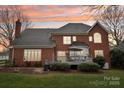 Brick home featuring a deck with seating, landscaped yard, and mature trees at 10506 Kenlauren Ter, Charlotte, NC 28210